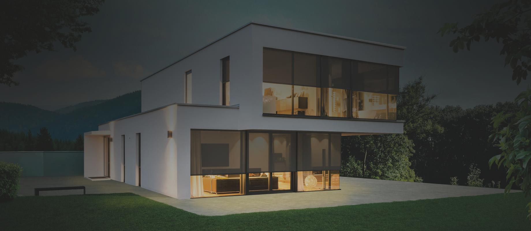 Modern model home in the twilight with interior lighting, textile screens