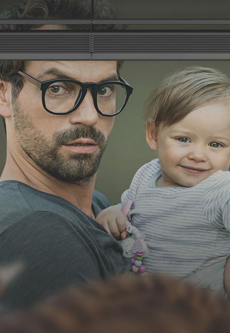 Man stands in front of the window with a baby in his arms