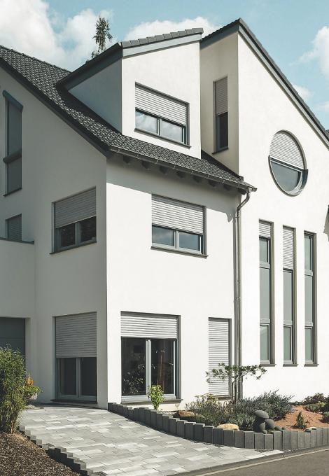 Three-storey single-family home with partly closed roller shutters by daylight