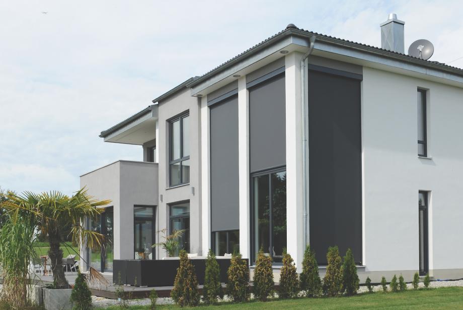 Single-family home by daylight with garden and partly lowered textile screens