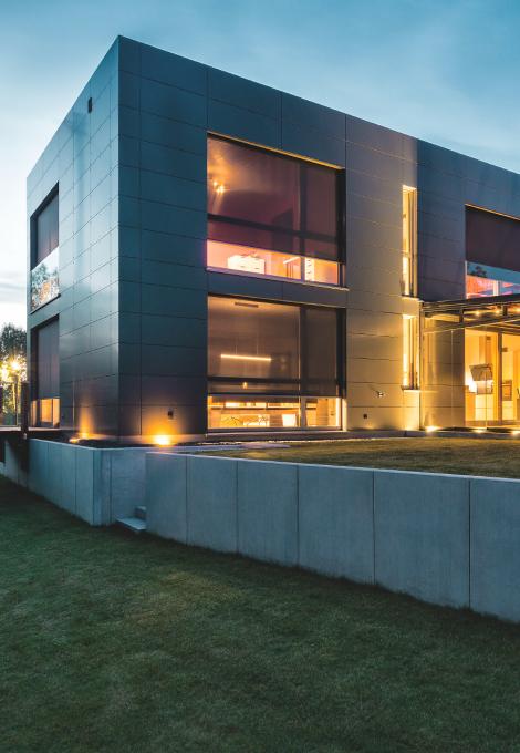 Modern house with interior lighting and lowered front-mounted textile screens in the twilight