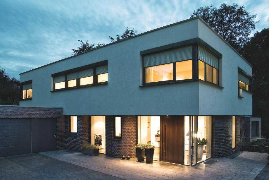 Home in the twilight with interior lighting and half closed roller shutters