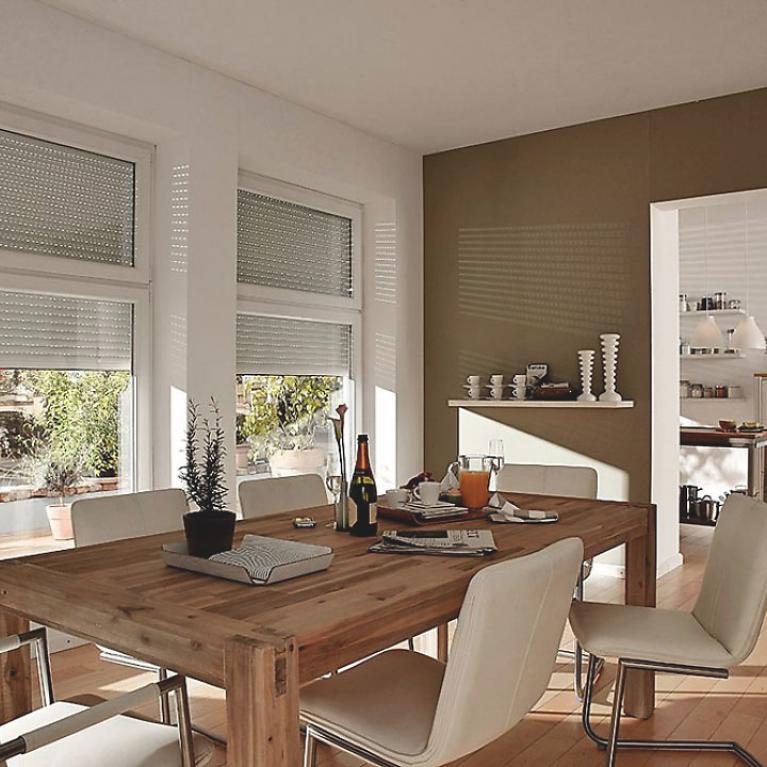 Dining room by daylight with half-closed roller shutters