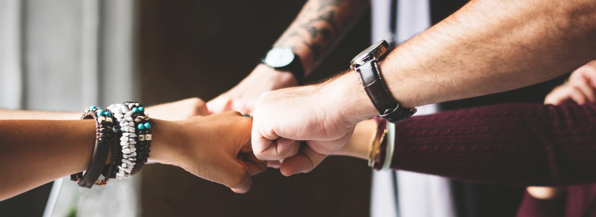 A group of people hold their fists together