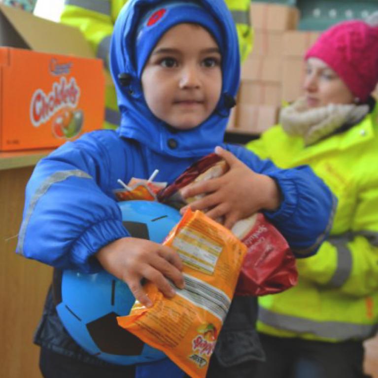 Santa Goes to Romania Child holds presents in its arms