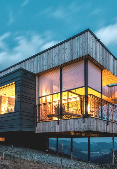 Modern house on a slope with wood and large windows with textile screens in the twiligth