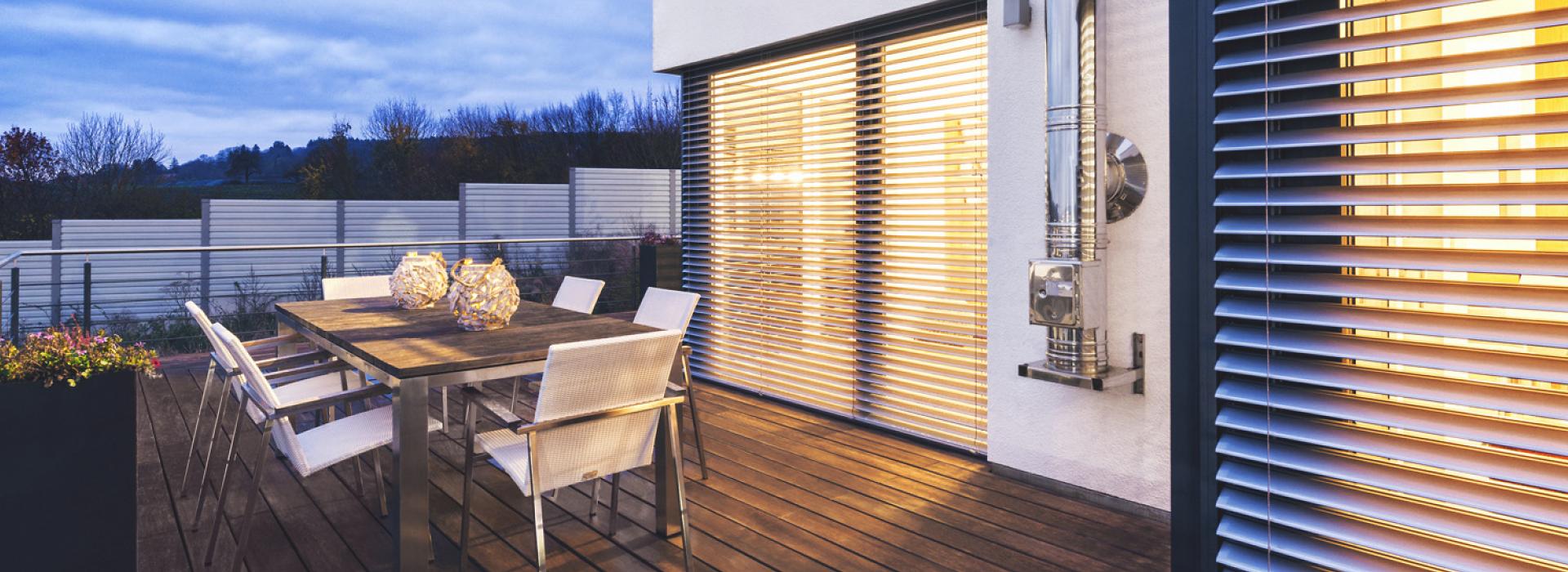 Patio with seating area in the twilight and with view to ROMA half opened external venetian blinds