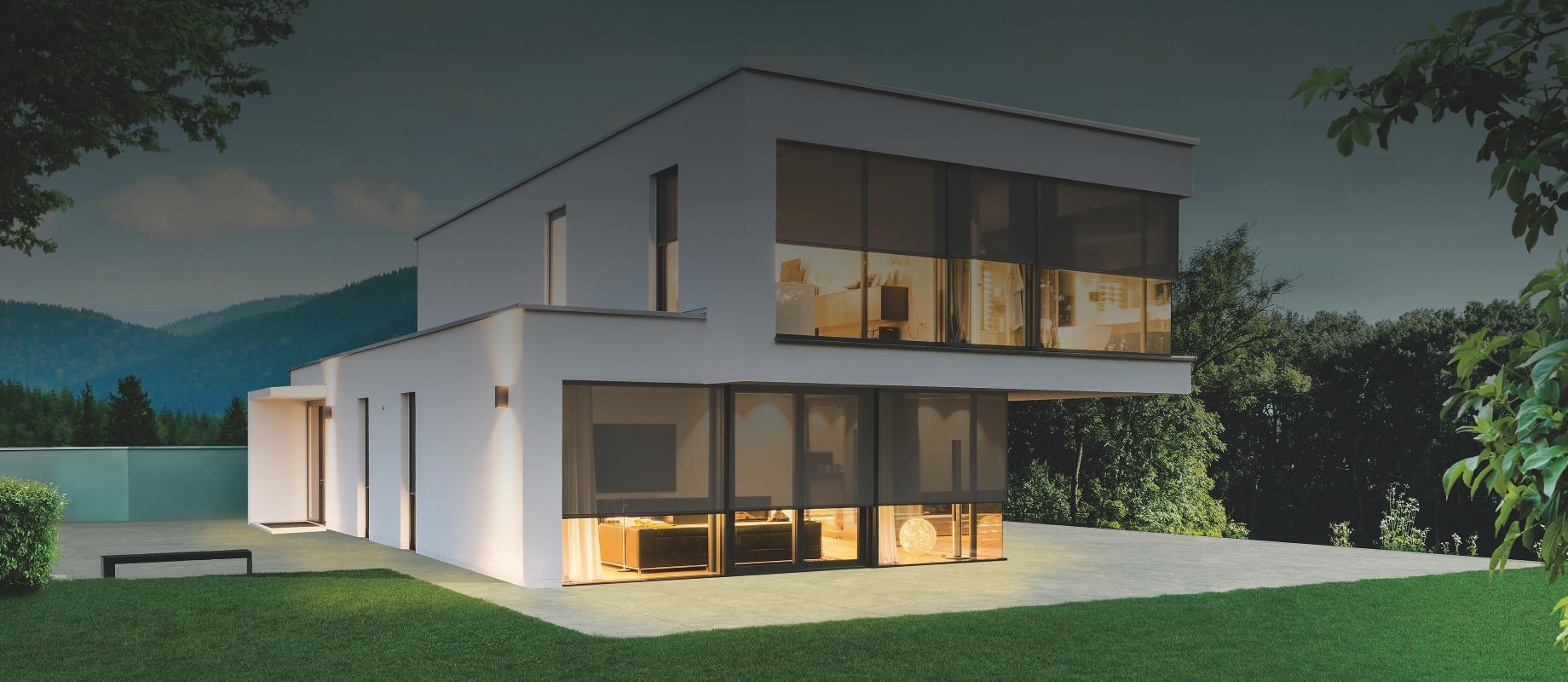 Modern model home in the twilight with interior lighting, textile screens