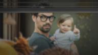 Man stands in front of the window with a baby in his arms