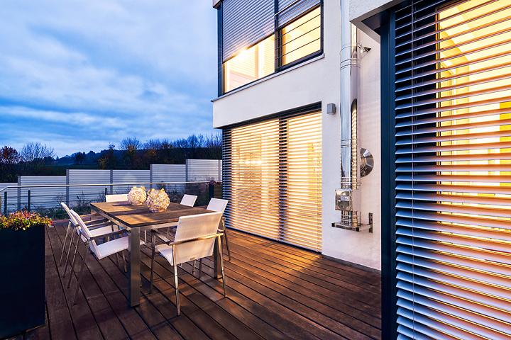 Patio with seating area in the twilight and with view to ROMA half opened external venetian blinds