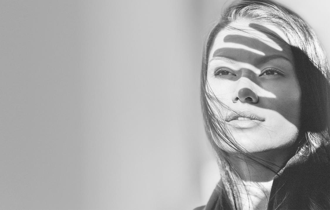 Woman is holding a hand against the light, black/white