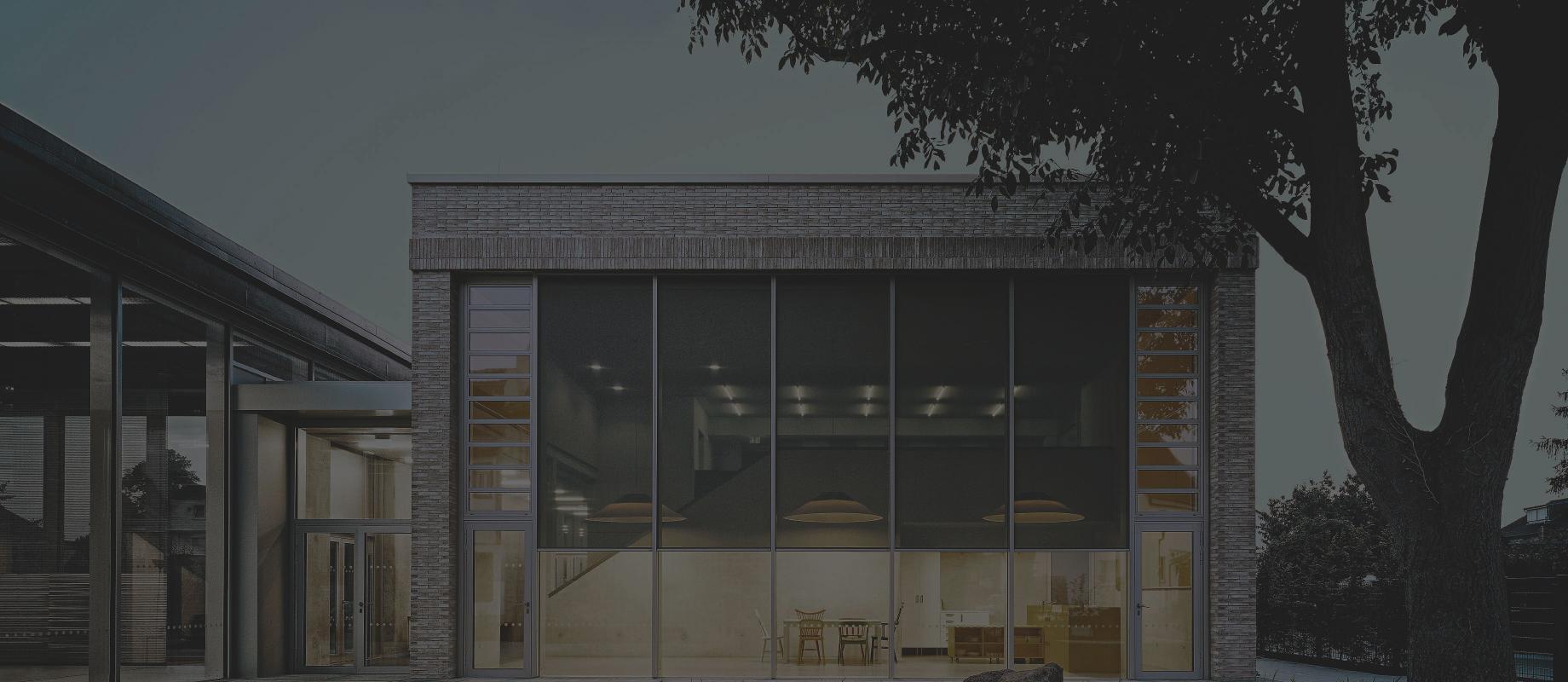 Day care center with glass front in the twilight with interior lighting and textile screens