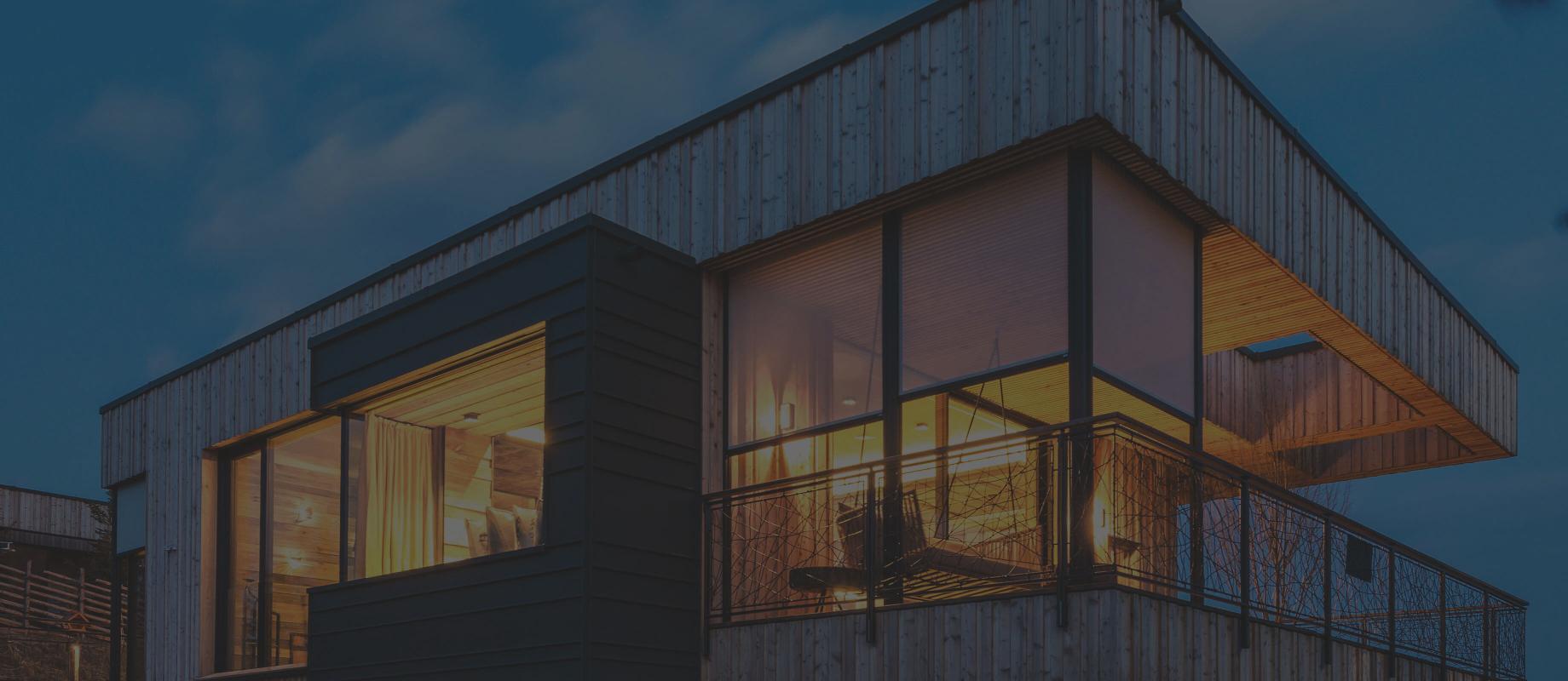 Modern house on a slope with wood and large windows with textile screens in the twiligth